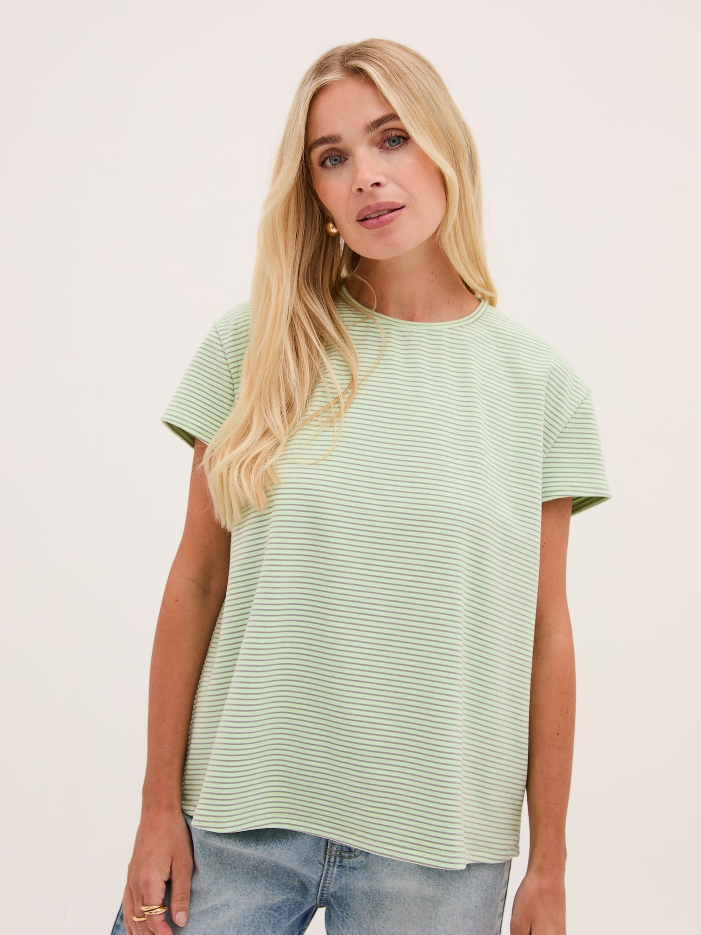 Woman wearing a light green t-shirt against a plain background