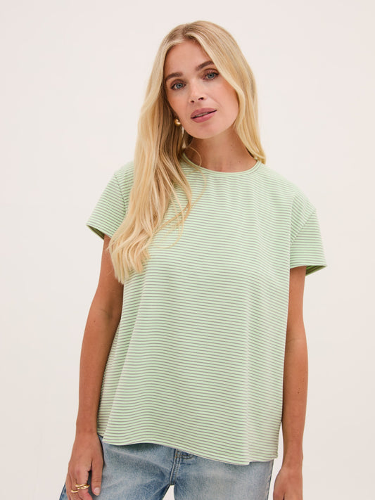 Woman wearing a light green t-shirt against a plain background