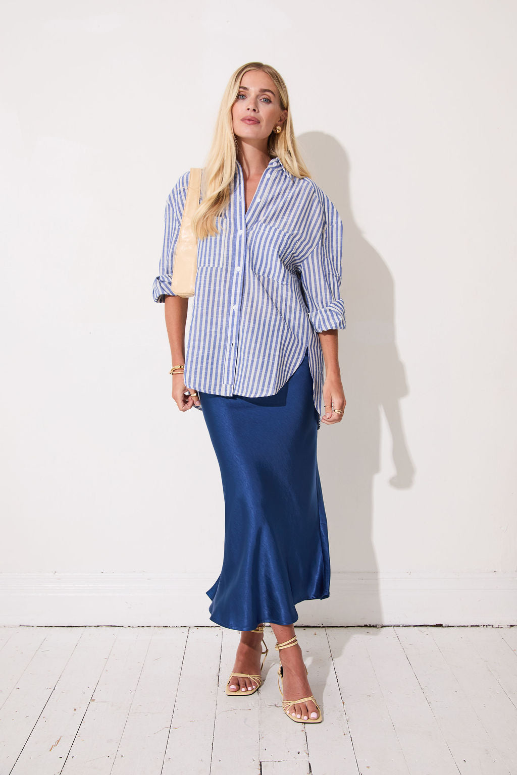 Woman wearing a blue and white striped shirt with a blue satin skirt on a white background